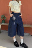 Person wearing a yellow crop top with animal prints and blue polka dot pants against a red wall.
