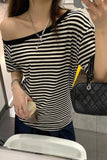 A person wearing a black and white horizontally striped off-the-shoulder t-shirt, paired with a black quilted shoulder bag and a silver necklace, captured in a mirror selfie.