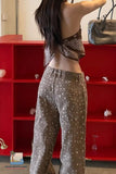 Person wearing a patterned top and pants in front of a red shelf.