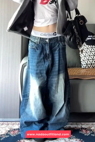Person wearing a white crop top, blue jeans, and a gray jacket with a visible brand logo.
