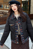 Woman wearing a black puffer jacket with a patterned scarf in an urban setting