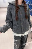 Person wearing a gray knitted cardigan with braided hair in an indoor setting