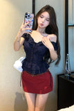 Woman taking a mirror selfie wearing a dark blue top and red skirt.