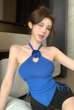 Woman wearing a blue top with a knot detail, sitting indoors.