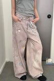 Person wearing light pink jeans with embroidered designs in a room.
