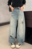Person wearing light blue jeans with cartoon designs indoors.