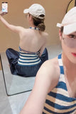 Woman taking a mirror selfie wearing a striped top and blue pants.