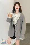 Woman wearing a gray blazer with lace details, holding a coffee cup indoors.