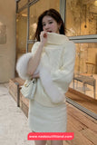 Woman wearing a white outfit with a fur vest in an indoor setting.