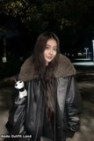 Person wearing a black leather jacket with a fur-lined hood, holding a stuffed panda toy, at night.