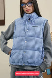 Person wearing a blue checkered puffer vest over a gray outfit with a visible brand logo.