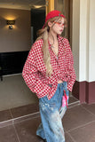 Person wearing a red checkered shirt and blue jeans standing indoors.