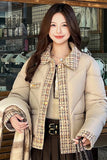 Woman wearing a beige puffer jacket with a patterned collar in a cafe setting