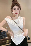 Woman in a white top with a black handbag in front of a beige wall