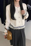 Person wearing a white blouse with black trim and a black pleated skirt, holding a brown handbag.
