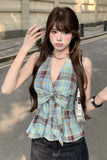 Woman wearing a plaid top with a bow detail on a street.