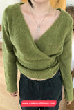 Person wearing a green sweater with a deep neckline, standing indoors.
