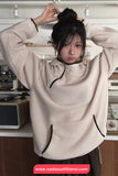 Person wearing a beige hoodie with black accents in a kitchen setting