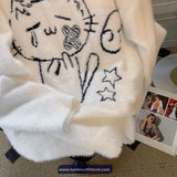 White fur coat with black embroidered design on a surface with a magazine underneath.