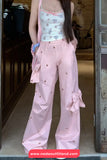 Person wearing a light blue top and pink pants with ruffles, standing indoors.