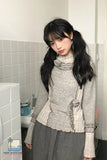 Person wearing a textured sweater and gray skirt in a bathroom setting