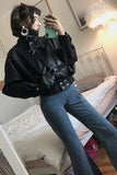 Person wearing a black leather jacket and blue jeans taking a mirror selfie.