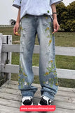 Person wearing floral embroidered jeans standing on a wooden deck with a grassy area and fence in the background.