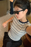 Person wearing sunglasses and a striped shirt sitting on a chair.