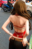 Woman in a red top with a unique back design on a street.