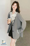 Woman wearing a gray cardigan with lace details, holding a coffee cup indoors.