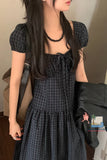 Person wearing a black plaid dress with a plain background