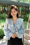 Woman wearing a light blue blouse with ruffled details in an outdoor setting