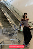 Woman standing next to a shopping cart in a mall setting