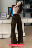 Person wearing a brown outfit with wide-leg pants in a modern kitchen.