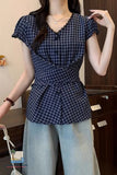 Person wearing a blue checkered top and light blue pants in an indoor setting.