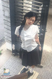Person wearing a white shirt and black skirt standing in front of a metal gate.