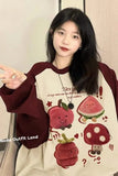 Person wearing a sweater with cartoon fruit designs and text.