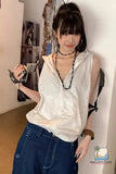 Person wearing a white sleeveless top and blue pants indoors.