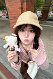 Person holding a plush toy and posing outdoors on a sidewalk.