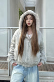 Person wearing a light gray hoodie and jeans standing outdoors.
