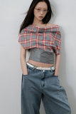 Person wearing a plaid top and jeans against a plain background
