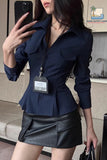Woman taking a mirror selfie wearing a navy pinstripe blazer and black leather skirt.