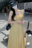 Woman in a yellow dress and cap at an airport, wearing a face mask.
