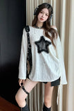 Woman wearing a white off-shoulder top with a black star design, black shorts, and knee-high black boots.