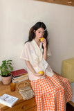 Woman sitting on a couch holding lemons in a casual setting with books and a plant.