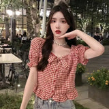 Woman wearing a red and white checkered blouse in an outdoor setting