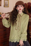Woman wearing a green lace-up blouse with a brown beret indoors.