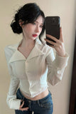 Woman taking a mirror selfie wearing a white blouse and blue jeans.