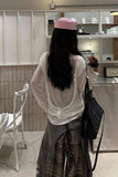 Person wearing a sheer white top and plaid pants in a kitchen setting.