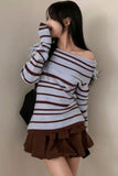 Woman wearing a striped sweater and brown skirt against a plain background